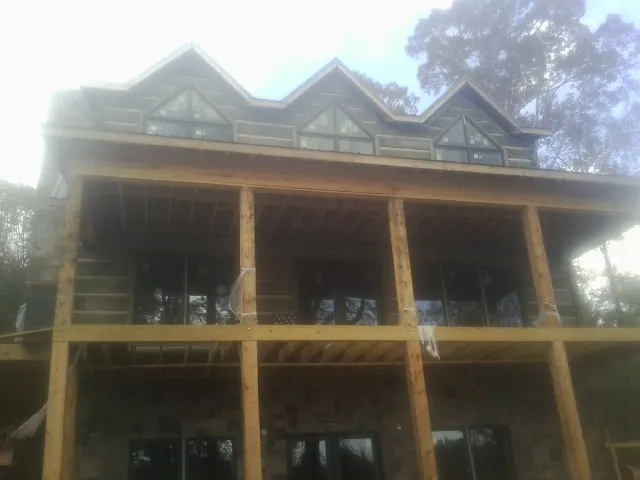 Dormers and porch framing on a large log home under construction — Roof Coating work by our crew in Chester